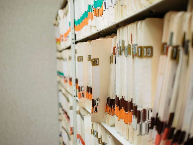 various medical record charts and folders in cabinet and on shelve sorted alphabetically and numerically